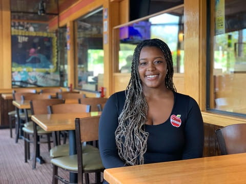 Female team member sitting at an Applebee's table smiling.